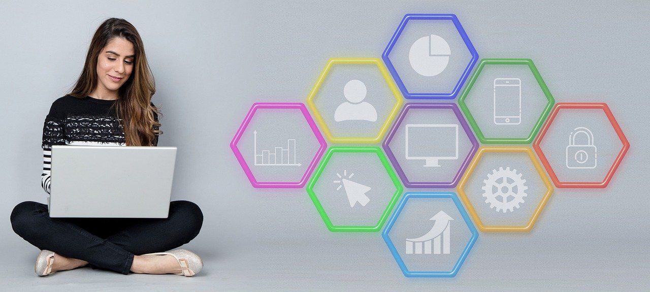 Woman sitting cross legged with a laptop beside colourful hexagon icons for users, security, settings and charts