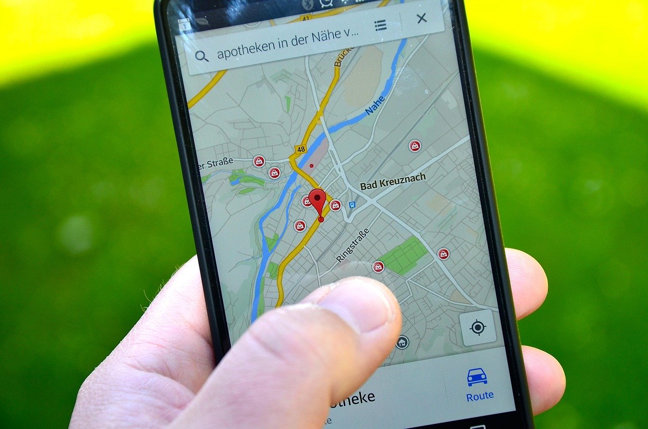 Hand holding a phone showing a local map search with red pins on nearby businesses and a route button