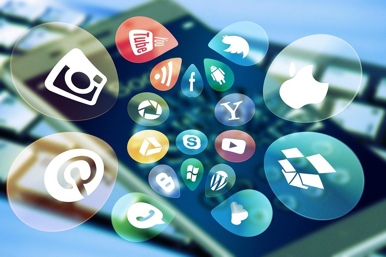 Cluster of glossy social media app icons, Facebook among them, floating above a blurred phone screen